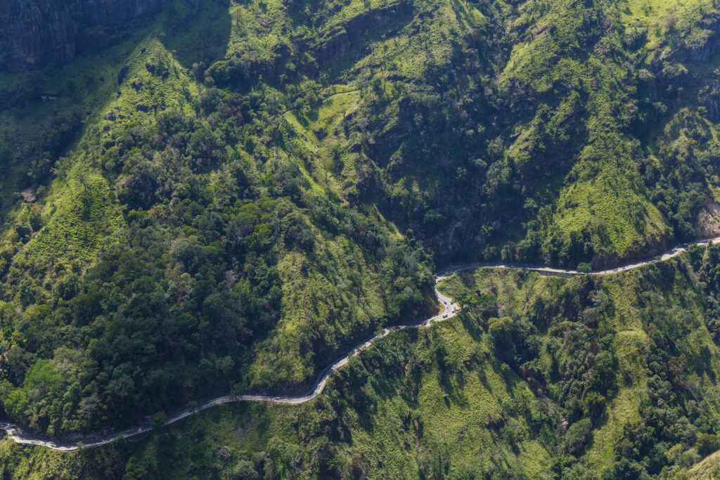 This aerial view showcases a picturesque landscape in Sri Lanka, likely the region around Ella. The winding road suggests adventure and exploration, making it a suitable destination for a family holiday.