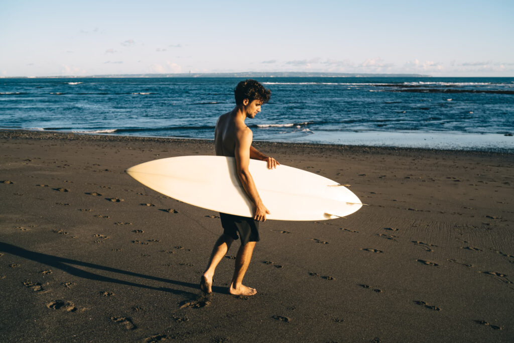 A surfer stands patiently on Hikkaduwa beach, their boards prepared, soaked in the warm glow of the setting sun.