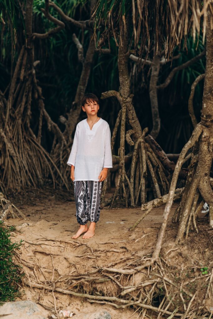 A little boy standing within the mangrove plants in Jungle beach, Sri Lanka.