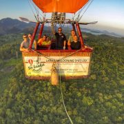 This image depicts a spectacular hot air balloon ride over Sri Lanka, showcasing the island's diverse beauty from a unique perspective with a breathtaking view created by lush green mountains, historic temples, and beautiful blue waters.